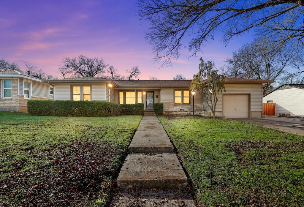 ranch-style house with a garage and a yard