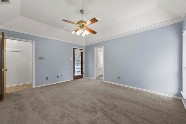 carpeted spare room featuring a raised ceiling, ceiling fan, and ornamental molding