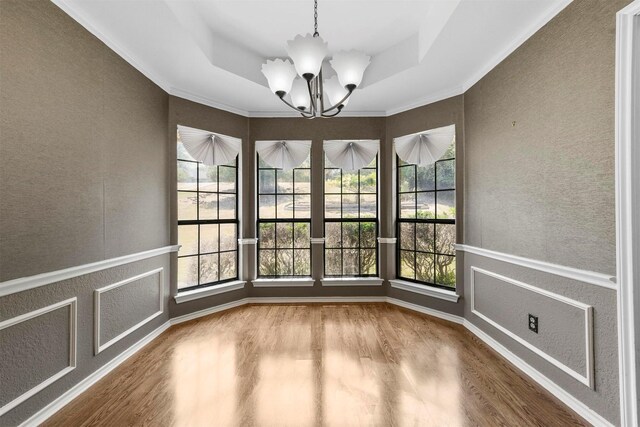 spare room featuring a notable chandelier, wood-type flooring, crown molding, and a tray ceiling