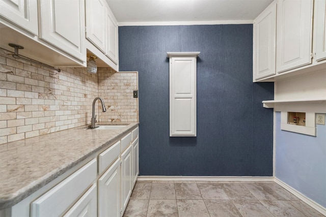 kitchen with tasteful backsplash, crown molding, sink, light tile patterned floors, and white cabinetry