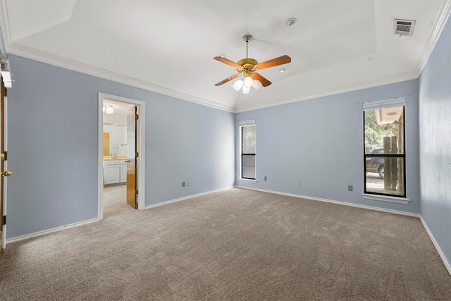 empty room featuring ceiling fan, light colored carpet, crown molding, and a tray ceiling