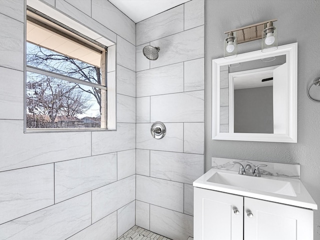 bathroom with a tile shower and vanity