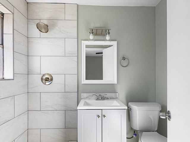 bathroom featuring tiled shower, vanity, and toilet