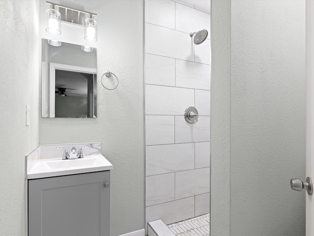 bathroom featuring vanity, ceiling fan, and a tile shower