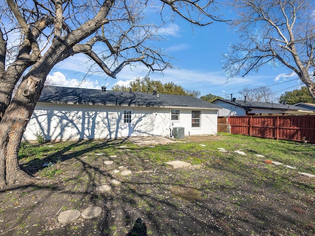 rear view of property with central AC and a yard