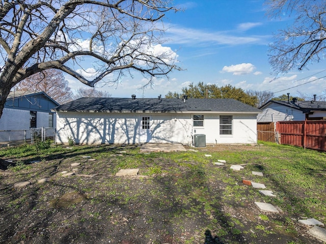 rear view of property with cooling unit and a yard