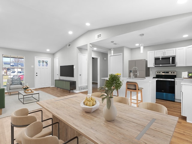 dining area featuring light hardwood / wood-style flooring, vaulted ceiling, and sink