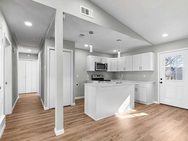 kitchen featuring hanging light fixtures, white cabinets, stainless steel appliances, and a kitchen island