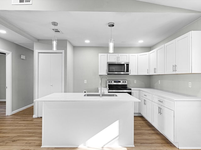 kitchen with pendant lighting, white cabinetry, stainless steel appliances, and a kitchen island with sink