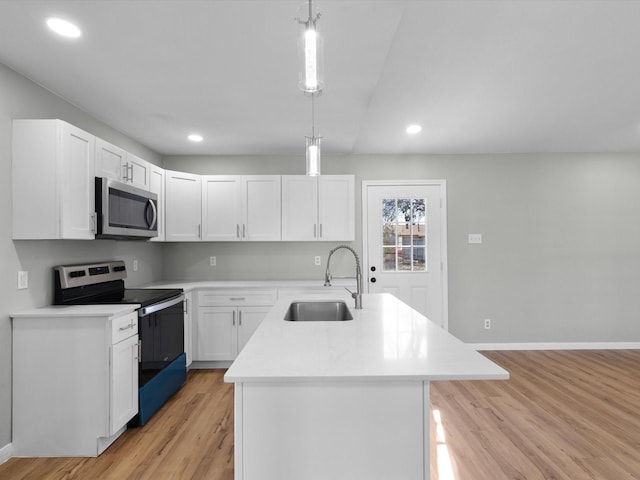 kitchen with decorative light fixtures, sink, appliances with stainless steel finishes, and an island with sink