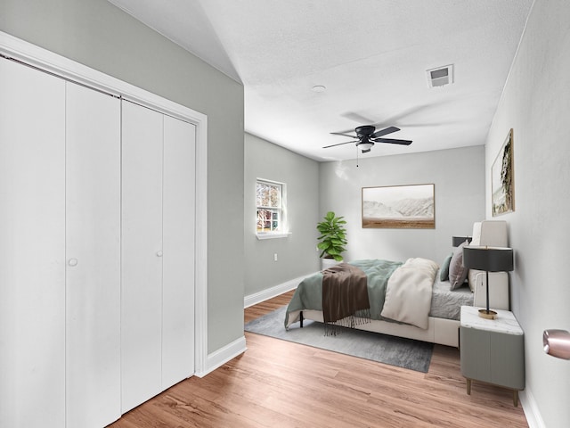 bedroom with ceiling fan, light hardwood / wood-style floors, and a textured ceiling