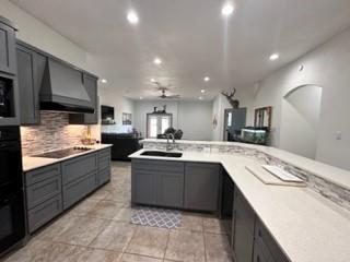 kitchen with sink, black electric cooktop, gray cabinetry, and wall chimney range hood