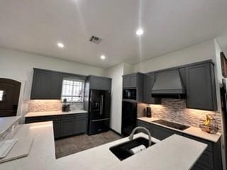 kitchen featuring black appliances, decorative backsplash, sink, and range hood