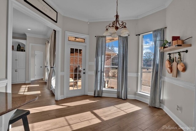 doorway featuring crown molding, a chandelier, and light hardwood / wood-style flooring