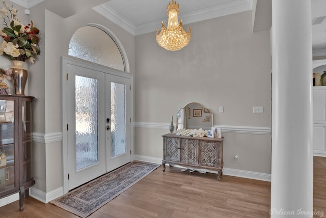 foyer featuring ornamental molding, a notable chandelier, light wood-type flooring, and french doors