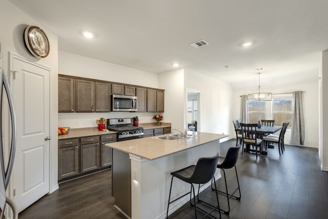 kitchen featuring appliances with stainless steel finishes, dark hardwood / wood-style flooring, a kitchen island with sink, sink, and decorative light fixtures