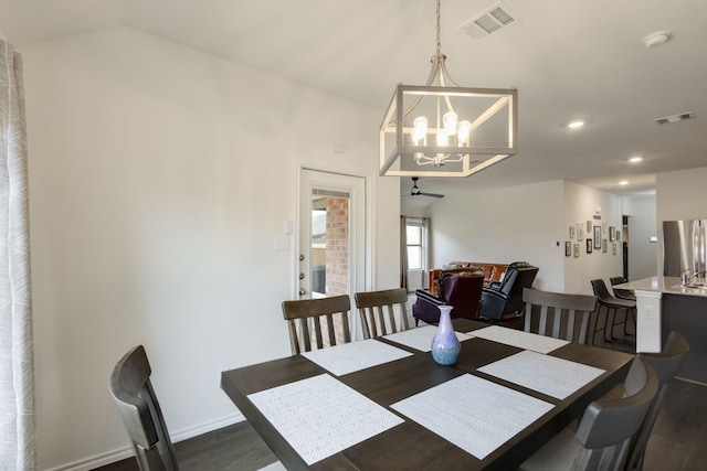 dining space featuring ceiling fan with notable chandelier, vaulted ceiling, and dark wood-type flooring