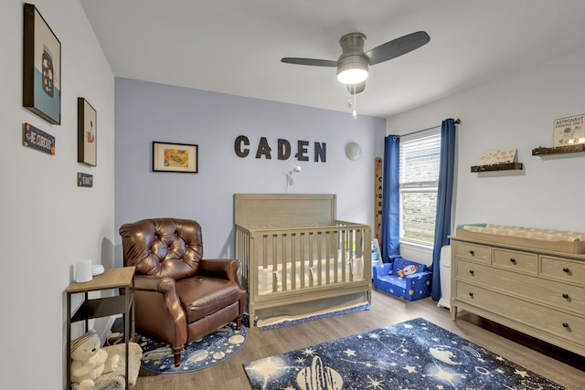 bedroom featuring ceiling fan, light wood-type flooring, and a nursery area