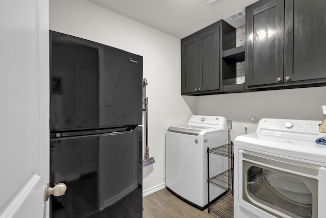 clothes washing area with cabinets, wood-type flooring, and separate washer and dryer