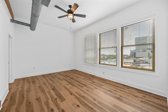 empty room featuring hardwood / wood-style flooring, ceiling fan, and a healthy amount of sunlight