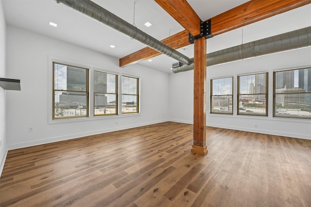 unfurnished living room with wood-type flooring and beam ceiling