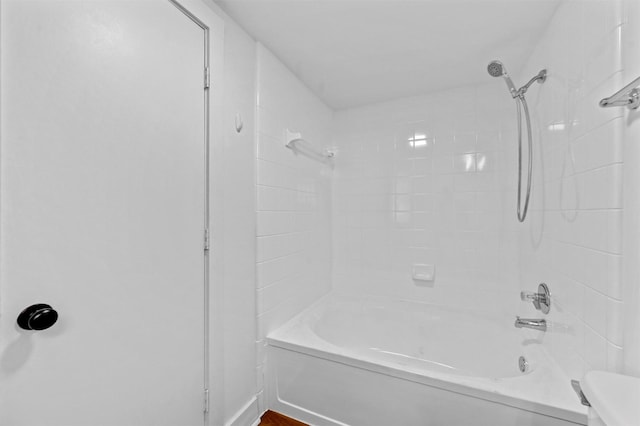 bathroom with toilet and tiled shower / bath