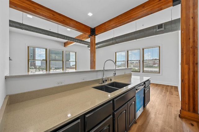 kitchen featuring light wood-type flooring, light stone counters, stainless steel dishwasher, sink, and beam ceiling