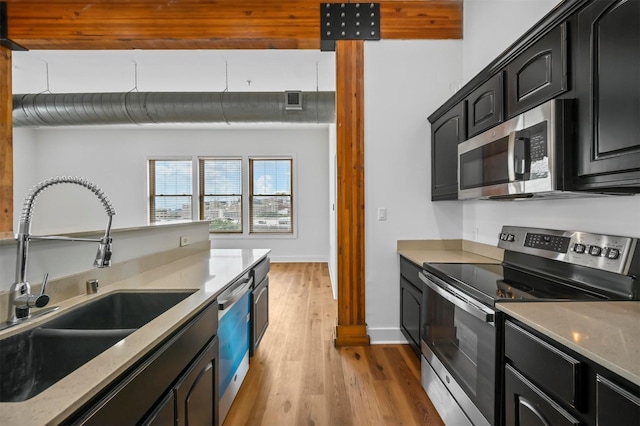 kitchen featuring light hardwood / wood-style floors, sink, appliances with stainless steel finishes, and decorative columns