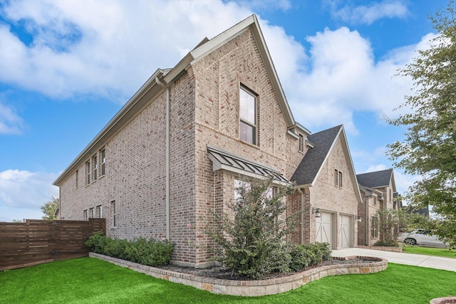 view of side of property featuring a lawn, concrete driveway, brick siding, and fence