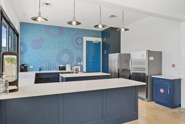 kitchen featuring kitchen peninsula, pendant lighting, blue cabinets, and stainless steel refrigerator