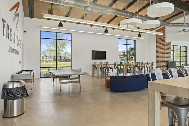 recreation room with concrete floors and a high ceiling