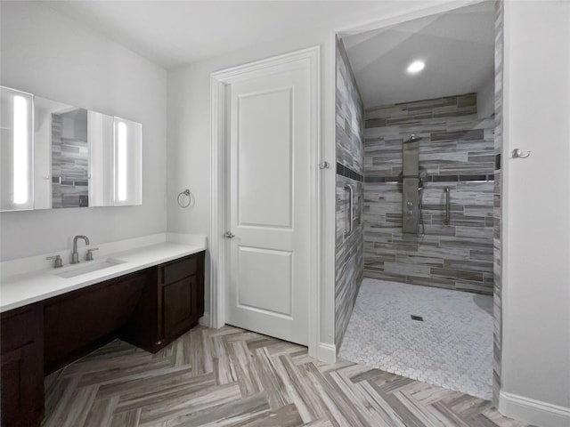 bathroom with parquet flooring, vanity, and a tile shower