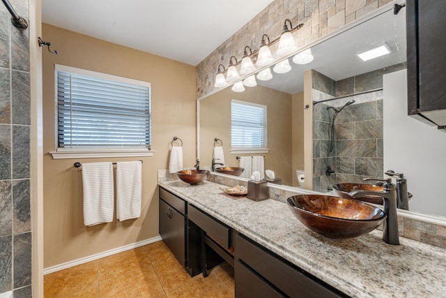 bathroom with tile patterned flooring, vanity, a tile shower, and toilet