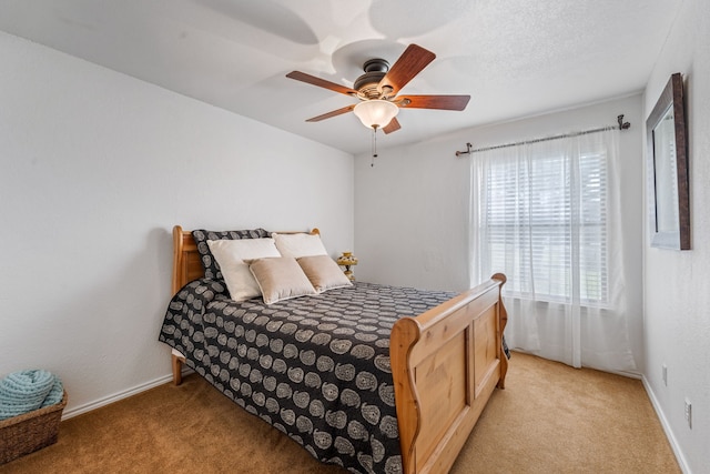 bedroom featuring ceiling fan, light colored carpet, and a textured ceiling