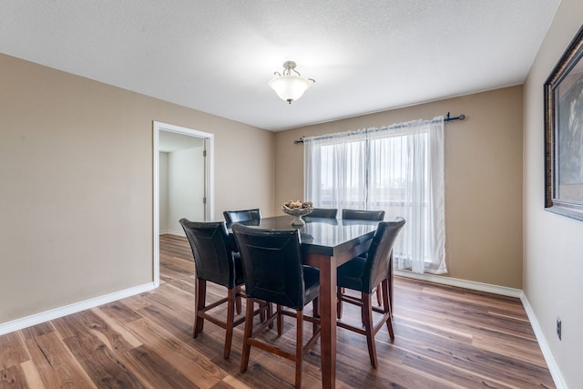 dining room featuring wood-type flooring and a textured ceiling