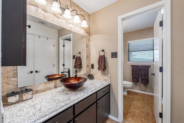 bathroom with vanity, toilet, and tasteful backsplash