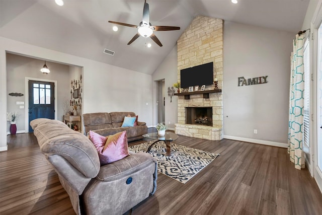 living room featuring a stone fireplace, ceiling fan, dark wood-type flooring, and vaulted ceiling