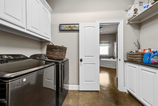 clothes washing area featuring separate washer and dryer and cabinets