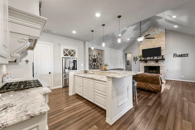 kitchen with a center island, hanging light fixtures, stainless steel appliances, a fireplace, and white cabinets