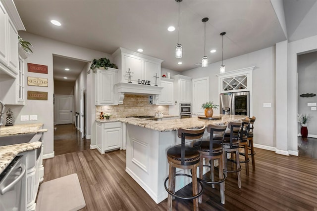 kitchen featuring white cabinetry, a kitchen island, hanging light fixtures, and appliances with stainless steel finishes