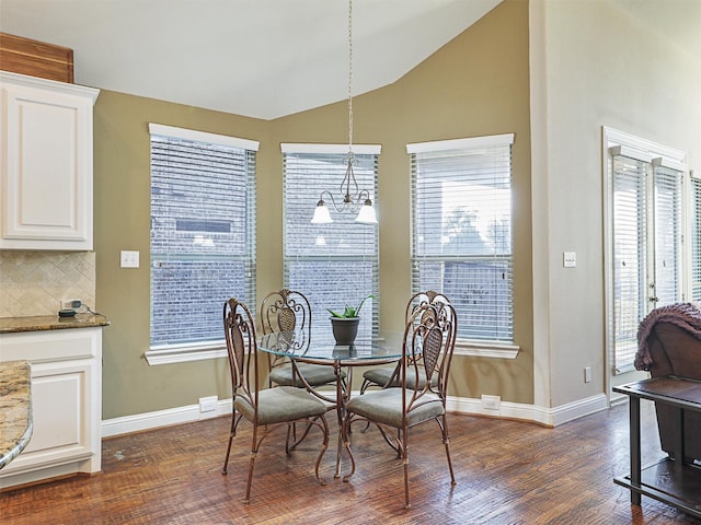 dining room featuring lofted ceiling, plenty of natural light, dark wood-type flooring, and a notable chandelier