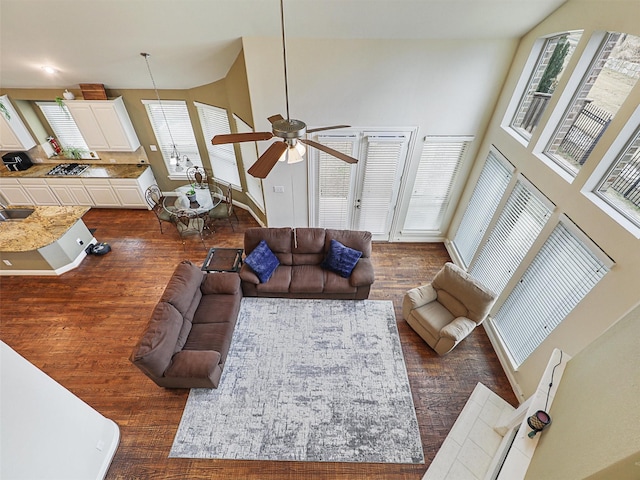 living room featuring sink, ceiling fan, a high ceiling, and dark wood-type flooring