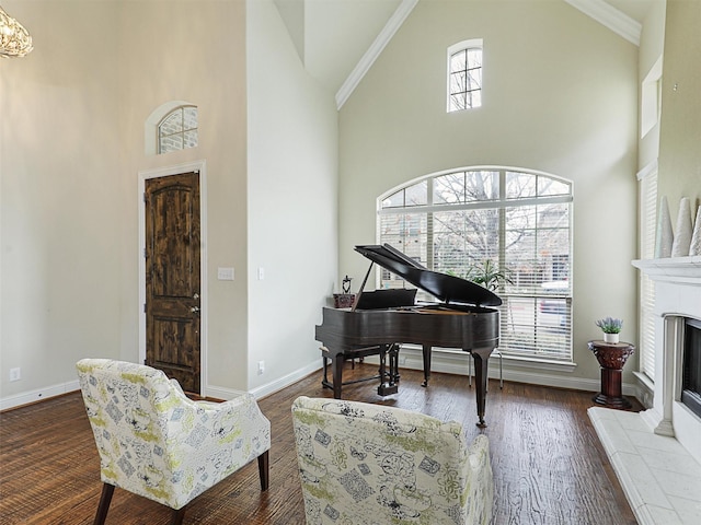 sitting room with high vaulted ceiling, dark wood-type flooring, ornamental molding, and a fireplace