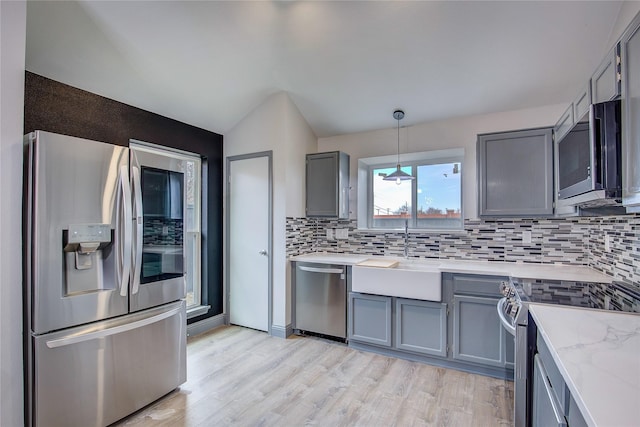 kitchen with lofted ceiling, sink, tasteful backsplash, decorative light fixtures, and appliances with stainless steel finishes