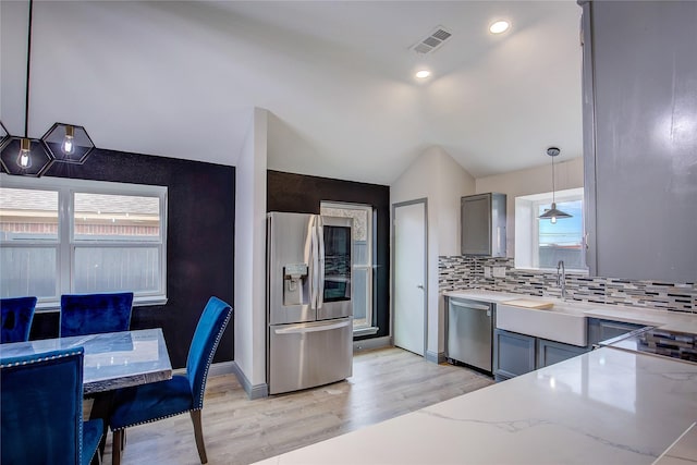 kitchen with stainless steel appliances, decorative light fixtures, light stone countertops, and gray cabinetry