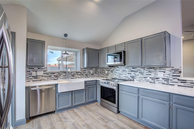 kitchen with lofted ceiling, sink, gray cabinetry, pendant lighting, and stainless steel appliances