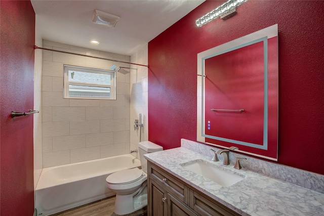 full bathroom with vanity, hardwood / wood-style flooring, toilet, and tiled shower / bath