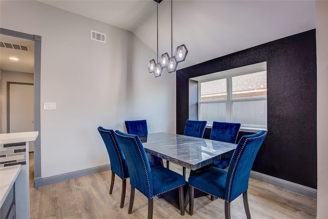 dining area with vaulted ceiling and light hardwood / wood-style floors