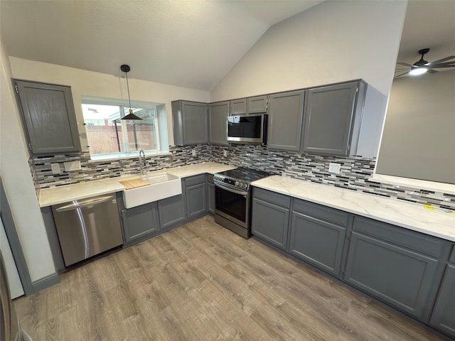 kitchen featuring sink, gray cabinetry, vaulted ceiling, and stainless steel appliances