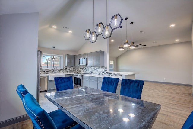 dining space featuring ceiling fan, lofted ceiling, and light hardwood / wood-style flooring